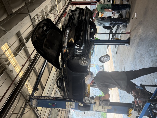 Technicians working on a black SUV in the bay