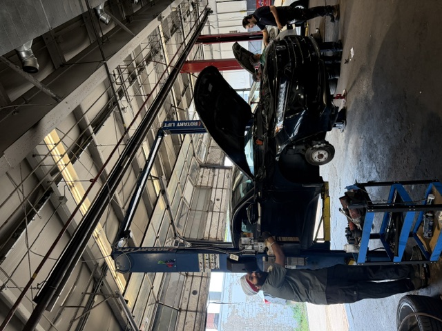 Black Honda raised on a two-post lift for repair